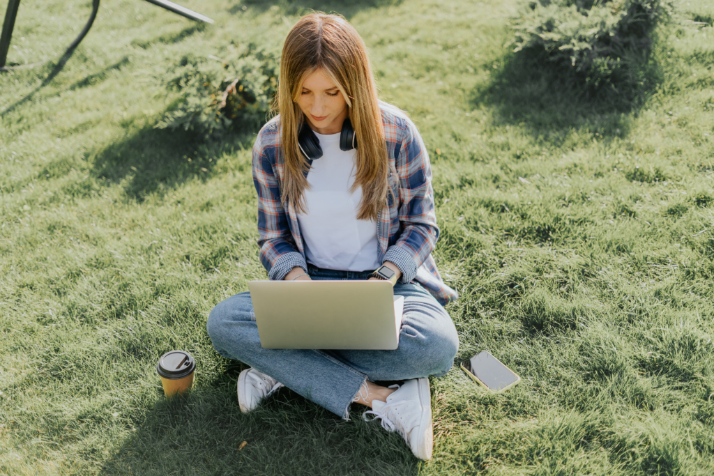 Woman using laptop sitting on the grass